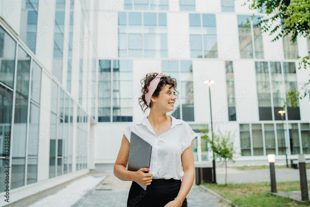 Wall mural young successful woman is going to work at modern business building