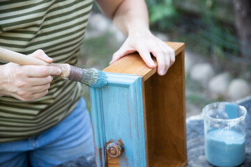 Painting a wooden furniture outdoors, an eco-friendly re-use business.