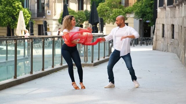 Passionate couple dancing salsa with energy on an urban street, showcasing stylish footwork and coordination
