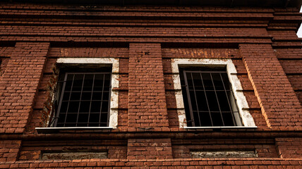 A Weathered Brick Building Notable for Its Gated Windows and Unique Architectural Styles