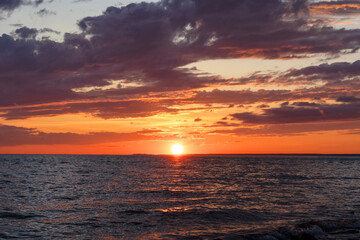 Seascape: sun setting over the horizon, reflected in the water