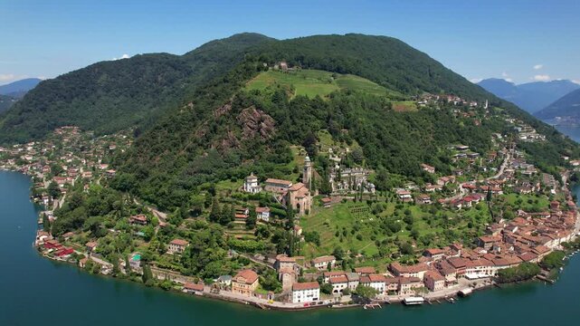 Morcote peninsula aerial view. Panoramic landscape of Lake Lugano and village 4K. Ticino Switzerland. Santa Maria del Sasso church. Scenic coastline.