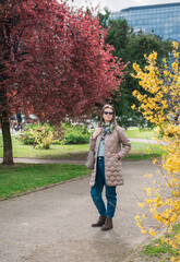 Obraz premium Beautiful stylish woman with sunglasses and bag walking in the city park