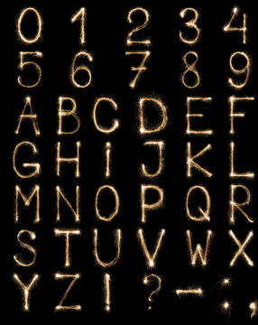 Full english alphabet and numbers set made from burning sparkles on black background. Shiny festive firework latin font.