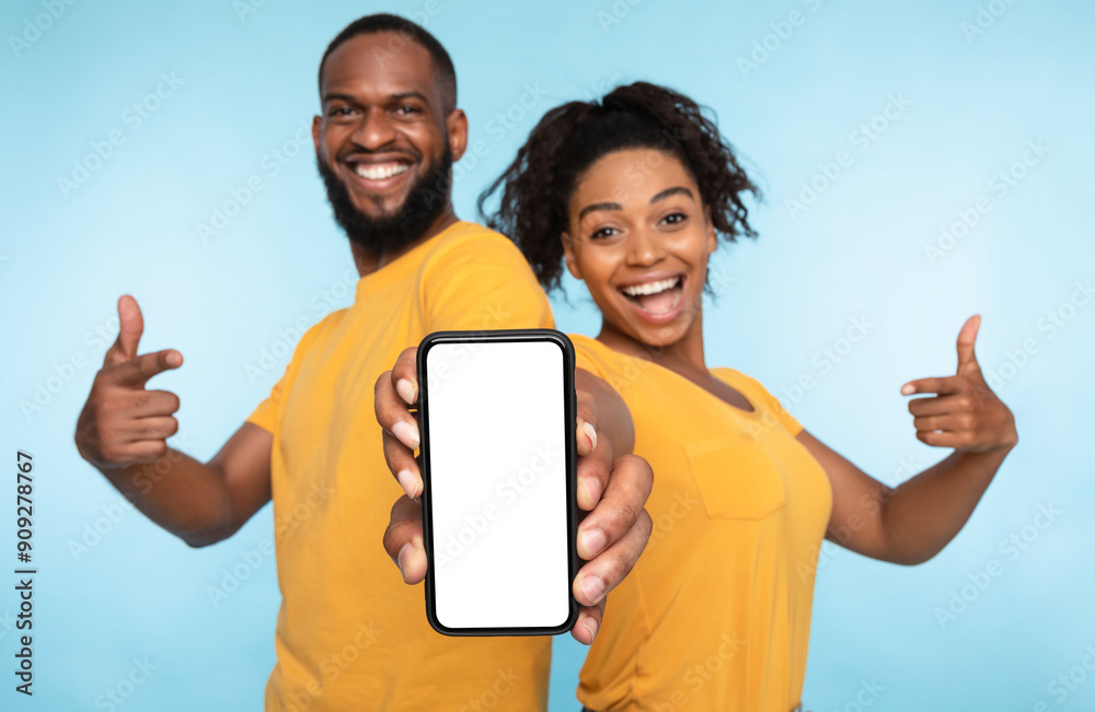 Poster use this new application. cheerful black couple pointing at smartphone with blank screen, recommendi