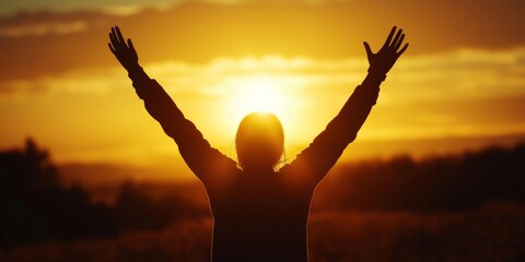 Fototapeta premium Golden Hour Gratitude: Silhouette of a person raising their arms in praise or celebration as the sun sets, bathing the scene in a warm, golden glow.