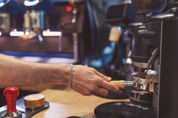 coffee beans ground and coffee powder pouring into holder with coffee machine at a cafe. machine and coffee bean in a cafe and restaurant counter. Professional coffee making, service and catering