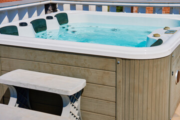 Outdoor hot tub on sunny rooftop deck with bubbling water and comfortable seating. Place for relaxation and leisure during summer vacations