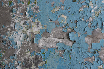 Blue peeling paint on the wall. Old concrete wall with cracked flaking paint. Weathered rough painted surface with patterns of cracks and peeling. High resolution texture for background and design.