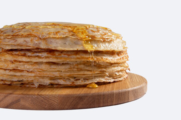 A stack of pancakes drizzled with honey. on a light background.