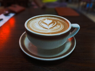 Barista-Designed Latte Art in Ceramic Cup: Aesthetic Coffee Scene with Soft Lighting on Wooden Table.
