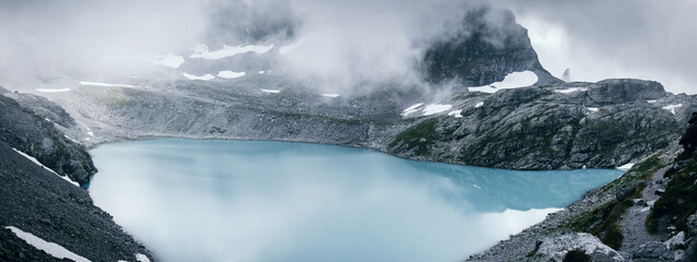 Panorama von speziellem türkisfarbigem kalten Bergsee mit dynamischen Wolken