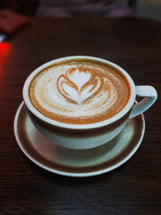 Symmetrical Floral Latte Art in Ceramic Cup: Close-Up Coffee Photography with Warm Wooden Table Setting.