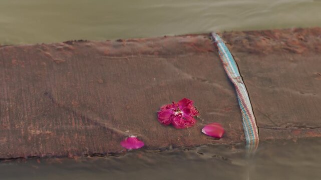 Close up of deflowered flower and piece of fabric tangled in concrete in river