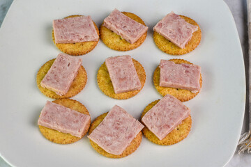 sliced spam  resting on whole wheat crackers