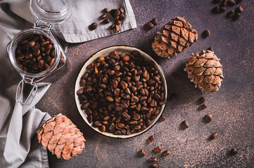 Ripe pine nuts in the shells on a plate and boiled pine cones on the table top view