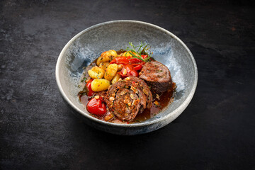Traditional slow cooked German wagyu beef roulades with vegetable and gnocchi served in spicy red wine sauce as close-up in a Nordic design plate with copy space