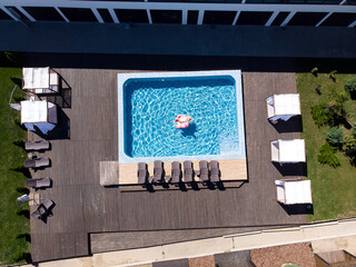Obraz premium Plus size woman relaxing on flamingo pool float in pool in hotel, aerial drone view. Summer holidays, enjoying summer vacations, luxury hotel