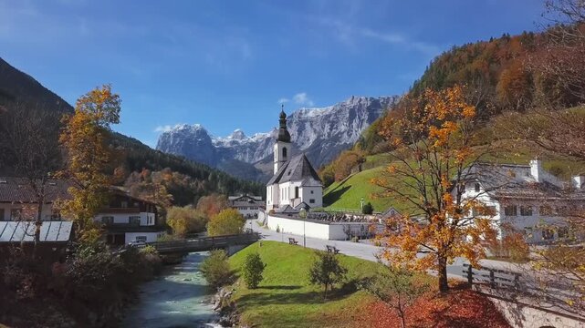 Flight over of footbridge near famous Parish church St. Sebastian, in Ramsau, Berchtesgaden, Bavarian Alps, Germany
