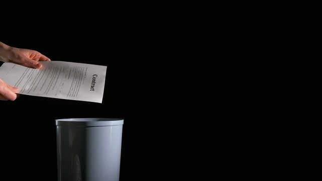 Throw the contract in bin. An angry office worker hands throw the business papers into the waste bin on the black background.