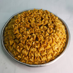 A white plate holds two delicious Turkish baklava rolls, generously filled with nuts and topped with pistachios.

