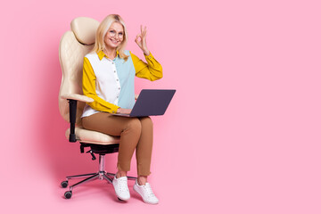 Full size photo of nice aged lady sit chair laptop okey symbol wear shirt isolated on pink color background