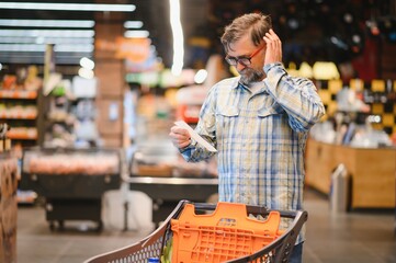 Shocked man looking at fiscal receipt in grocery store