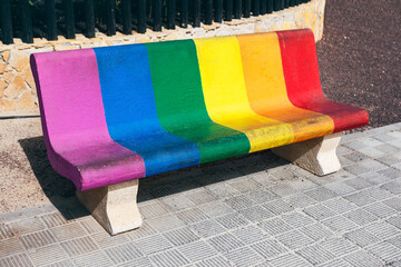 Bench with the colors of the rainbow painted on it. Wooden seat painted in rainbow colors, adding a...