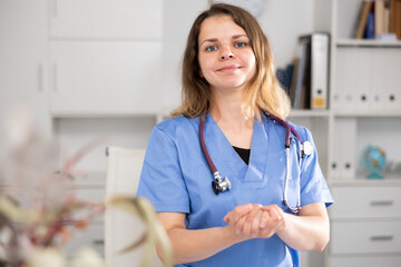 Portrait of therapist woman who is standing on her workplace in the clinic