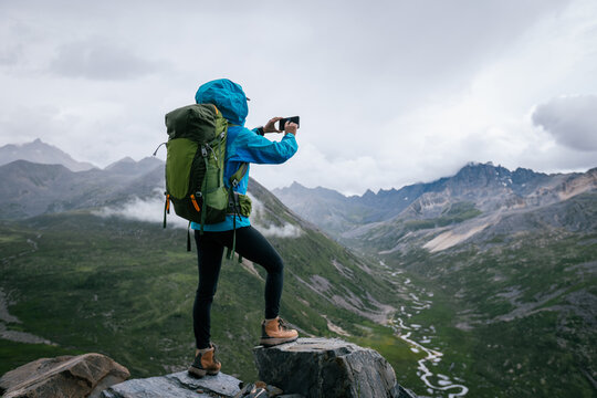 Hiking woman taking photo with samrt phone on high altitude mountain top