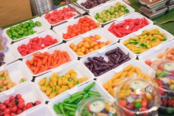 A table full of colorful peppers and other fruits. The peppers are in different colors and sizes, and they are arranged in various containers. Scene is cheerful and vibrant, as the colorful peppers