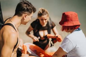 Three friends inflating an orange raft together by a lake, getting ready for a fun and adventurous...
