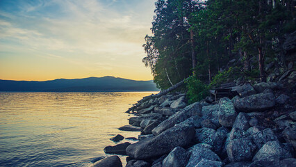 The shore of Lake Turgoyak. The natural landscape. Lake, rock, hills on the horizon. Sunset on the lake