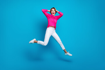Full length photo of excited funky lady dressed pink knitted shirt jumping high hands arms head isolated blue color background
