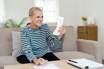 Senior Woman Reviewing financial at Home with Calculator and Document in Living Room