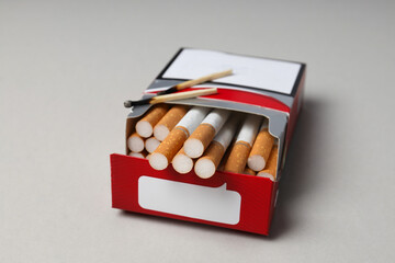 A pack of cigarettes with matches on a light background