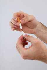 Broken cigarette in male hands on a light background