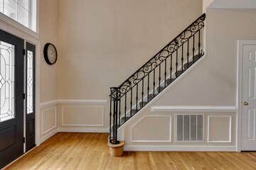 Elegant Staircase With Ornate Railing In A Brightly Lit Entryway Area