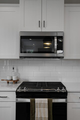 Fototapeta premium Modern Kitchen With Microwave, White Cabinets, And Black Stove