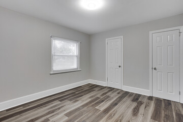 Minimalist Room With Light Walls And Wooden Flooring Offering Two Closets