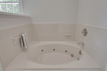 White Bathtub Surrounded By Pale Pink Tiles Situated In A Spacious Bathroom