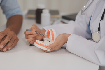 Obraz premium Dentist consultation - patient visit at the dental clinic office. Female dentist wearing dentures to explain teeth Recommend guidelines for orthodontics Dentist giving advice on patient's condition