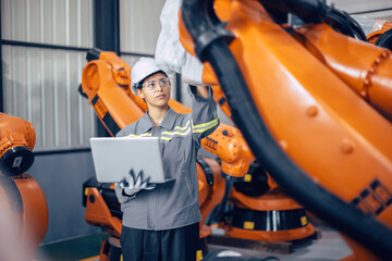 Engineer woman working in advance machine factory. Indian female engineering staff work checking robot arm in assembly plant