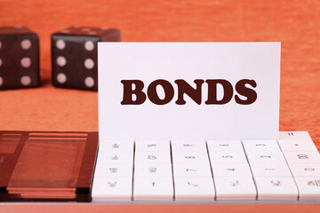 BONDS word on a business card on a calculator in front of an orange background