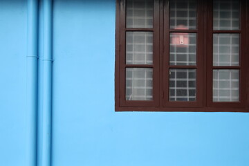 A normal household in Kerala with blue wall and simple wooden window design