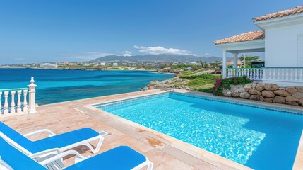 Luxurious oceanside villa with private pool, offering stunning views of the sea and mountains under a clear blue sky.
