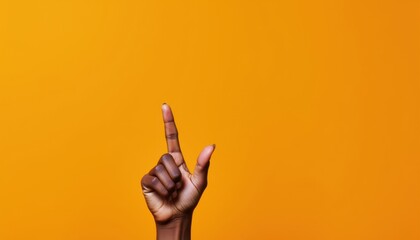 Fototapeta premium Close-up of a hand with an extended forefinger against a bright orange background.