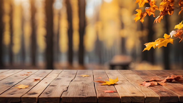 Wooden table with leaves on a blurred autumn park background. Autumnal scene