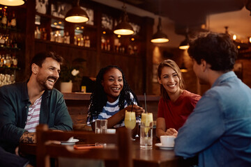Multiracial group of happy friends talking in café.