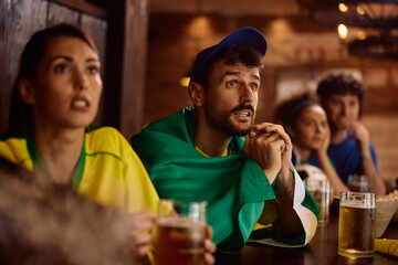 Young sports fan watching  match with anticipation in  pub.